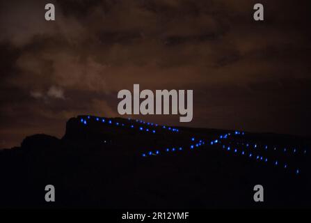 Lichter von den Läufern auf dem Gipfel von Arthurs Seat während einer NVA Speed of Light Produktion auf dem Hügel in Edinburgh, Schottland, stehen Schlange, um das zu reflektieren Stockfoto