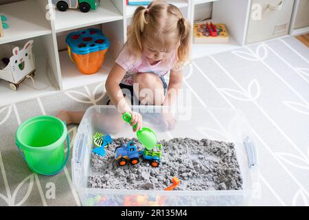 Kleines Mädchen, das mit kinetischem Sand spielt. Sinneskiste für Kinder Stockfoto