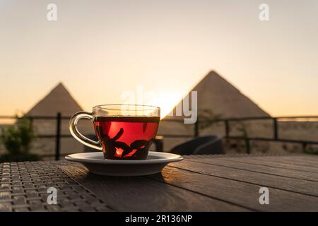 Glaskrug mit Tee auf einem schönen Hintergrund der wichtigsten Sehenswürdigkeiten Ägyptens, der Großen Pyramiden von Gizeh. Stockfoto
