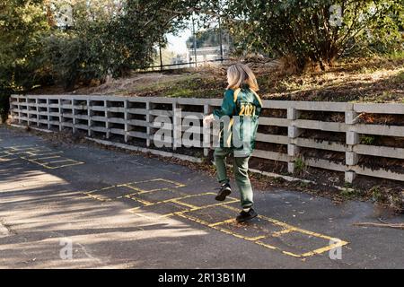 Eine australische Grundschülerin, die in der Pause auf dem Schulhof Hopscotch spielt Stockfoto