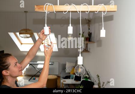 Junge Frau, die zu Hause Glühbirnen wechselt. Stockfoto