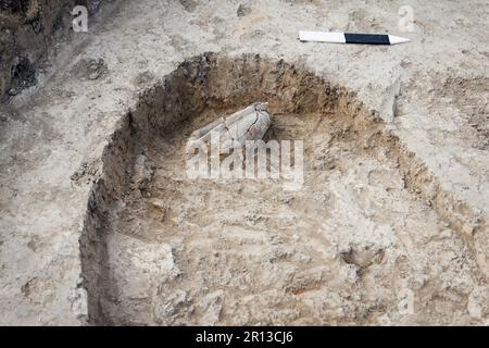 Archäologische Ausgrabungen, Archäologen arbeiten, graben ein antikes Tonartefakt aus. Lineale zeigen Größe, Tiefe und Maßstab der gefundenen Arbeit und Elemente an Stockfoto