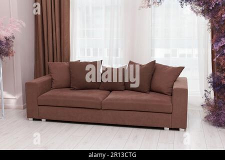 Wunderschönes braunes Sofa mit fünf Kissen, Teil der modernen Inneneinrichtung im Wohnzimmer Stockfoto