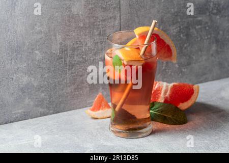 Eistee mit Eis, Minze und Grapefruit. Ein kühles erfrischendes Getränk mit Zutaten auf grauem Hintergrund. Speicherplatz kopieren. Stockfoto