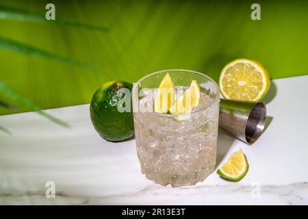 Kalt geeister Ti-Punsch-Alkohol-Cocktail, kleiner Punsch, Rum-basiertes Mixgetränk mit frischen Limettenscheiben, auf farbigem grünen Hintergrund Stockfoto