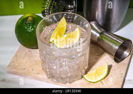 Kalt geeister Ti-Punsch-Alkohol-Cocktail, kleiner Punsch, Rum-basiertes Mixgetränk mit frischen Limettenscheiben, auf farbigem grünen Hintergrund Stockfoto