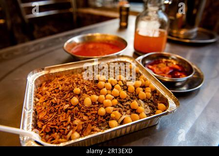 Koshary, Kushari oder Koshari ist das beliebteste kulinarische Gericht in Ägypten, eine Mischung aus Pasta, Reis, Linsen, Kichererbsen und gebratenen Zwiebeln, garniert mit Tomaten- und Knoblauchsoße. Stockfoto