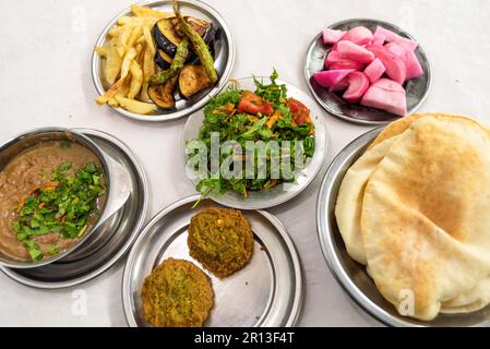 Kairo, Ägypten. 03. Dezember 2022. Ein Tisch mit typisch ägyptischem Street Food von Fuul und Falafel mit Salat, Pickles und lokalem Brot, gesundem und billigem Essen in ganz Ägypten. (Foto: John Wreford/SOPA Images/Sipa USA) Guthaben: SIPA USA/Alamy Live News Stockfoto