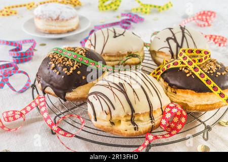 traditionelles deutsches Berliner Gebäck mit dunkel-weißer Schokolade und sprödem Haselnuss, dekoriert für Party oder Karneval Stockfoto