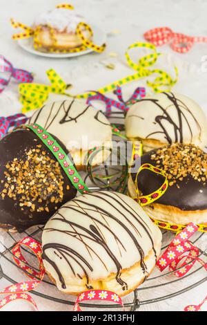 traditionelles deutsches Berliner Gebäck mit dunkel-weißer Schokolade und sprödem Haselnuss, vertikal für Party oder Karneval dekoriert Stockfoto