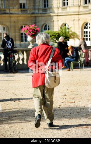 Eine alte Dame, die im Luxemburger Garten spaziert. Rückansicht. Urbane Szene. Paris (Frankreich) Schwarzweiß. Stockfoto