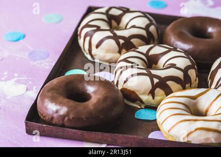 Schokoladen-Donuts, Berliner, Krapfen auf einem rostigen Tablett auf pinkfarbenem Hintergrund Stockfoto