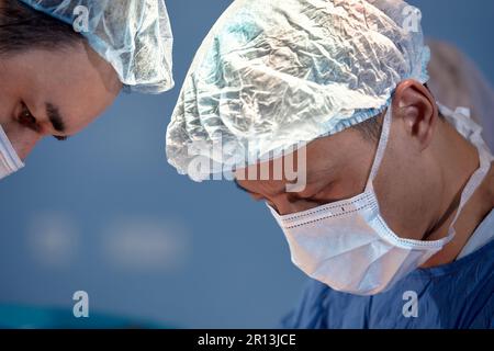 Gesichter von Chirurgen Nahaufnahme während einer komplexen und intensiven Operation retten Ärzte das Leben des Patienten, Teamarbeit von Chirurgen. Stockfoto