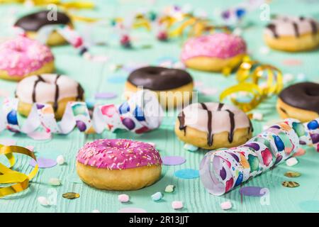 Donuts, Berliner, Krapfen mit Bändern und Konfetti. Farbenfrohes Bild von Karneval, Geburtstag und fasching, grüner Hintergrund Stockfoto