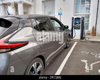 Ein Nissan Leaf Elektrofahrzeug, das mit einem BP Pulse Schnellladegerät auf einem Hotelparkplatz in Northam, North Devon, England, aufgeladen wird. Stockfoto