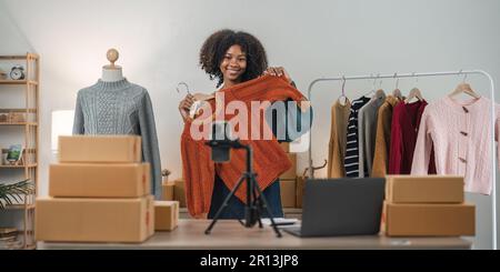 Vlogger, Blogger, kleines KMU-Unternehmen, asiatische Schönheit, die Livestreaming von Mobiltelefonen verwendet, um Kleidung zu verkaufen, Livestream verkauft, online verkauft, Produkt zeigen Stockfoto