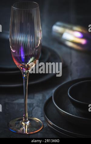 Rosafarbenes Champagnerglas und schwarzes Steingut auf einem rustikalen schwarzen Tisch, vertikal Stockfoto