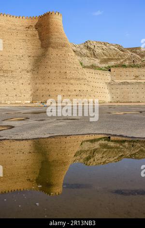 Massive Mauern der Arche bukhara spiegeln sich nach kürzlichem Regen in der Wasserpfütze wider Stockfoto