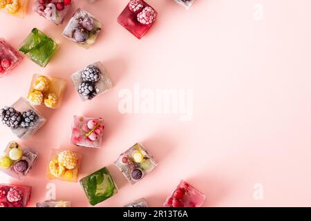Frozen ice cubes with various fruits, blackberries and raspberries, gooseberries and currants, blueberries and mint, top view Stockfoto