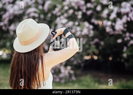 Photographers Day, professioneller Fotograf, der im Park Fotos oder Fotos im Freien macht. Fotografin mit einer großen professionellen Kamera Stockfoto
