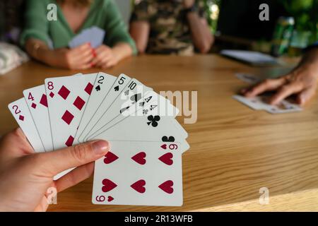 Eine Frau, die mit Freunden Karten spielt. Stockfoto