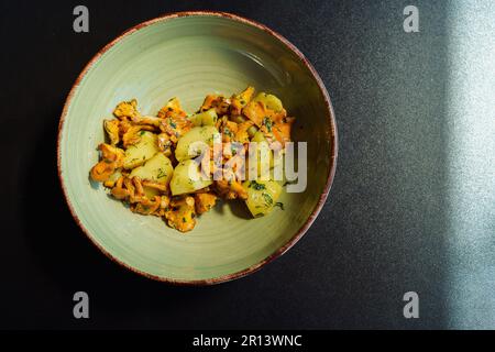 Ein Teller mit einem vegetarischen Mittagessen der Saison. Pfifferlinge von Wildpilzen, in Pflanzenöl mit gekochten Kartoffeln und frischem Dill und Petersilie gebraten Stockfoto