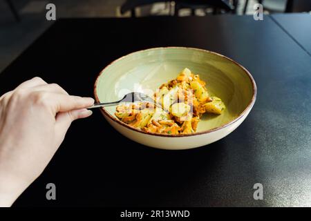 Eine Frau isst ein frisches, vegetarisches Mittagessen der Saison. Gebratene Wildpilze, Pfifferlinge mit gekochten Kartoffeln und Kräutern. Stockfoto