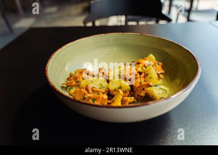 Gebratene Pfifferlinge mit gekochten Kartoffeln und grünen Kräutern, Petersilie und Dill in einer Schüssel zum Mittagessen. Stockfoto