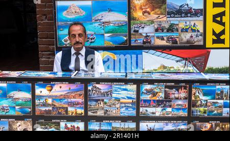 Ein düsterer Türke sitzt hinter einem Touristenschalter in den Straßen der Altstadt von Kaleici in Antalya, Türkei (Turkiye). Sein dicker schwarzer Schnurrbart und Stockfoto