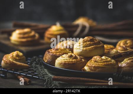 Zimtrollen auf einem schwarzen Tisch auf dunklem Holzhintergrund Stockfoto