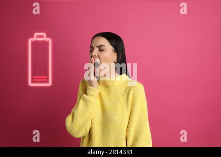 Müde Frau gähnt und Abbildung einer entladenen Batterie auf pinkfarbenem Hintergrund Stockfoto