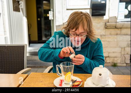 Porträt einer glücklichen 40-Jährigen mit Down-Syndrom, die Tee in einem Restaurant, Tienen, Belgien, braut Stockfoto