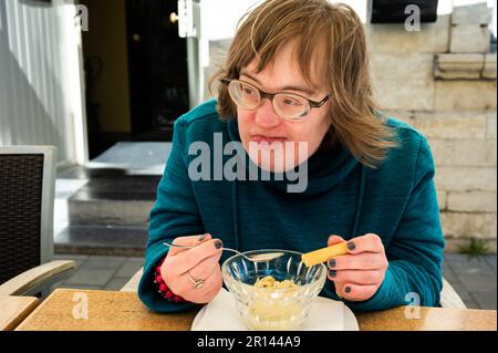 Porträt einer glücklichen 40-Jährigen mit Down-Syndrom, die ein Eis isst, Tienen, belgien Stockfoto