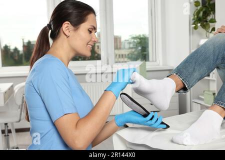 Schöne Orthopädin-Einlegesohle am Fuss des Patienten im Krankenhaus Stockfoto