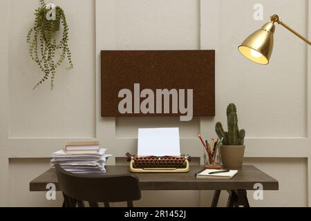 Schreibmaschine und Papierstapel auf dunklem Tisch im Zimmer. Schreibarbeitsplatz Stockfoto