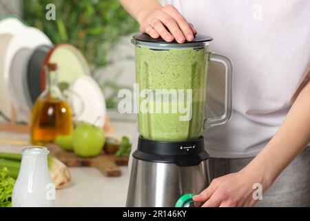 Eine Frau bereitet leckeren grünen Smoothie in der Küche zu, Nahaufnahme Stockfoto