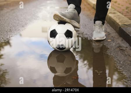 Mann mit Fußball in der Nähe der Pfütze, Nahaufnahme Stockfoto