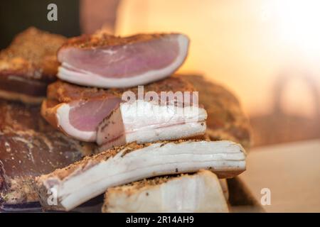 Geräucherter Schinken mit geräuchertem Speck. Schinken und Speck sind auf dem Markt zum Verkauf bereit. Sie sind beschriftet Stockfoto