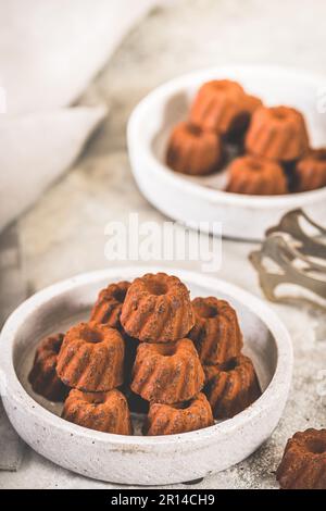 Schokoladenpralinen in Form von kleinen Guglhupf-Törtchen, mit Kakao bestaubt, auf hellgrauem Hintergrund Stockfoto