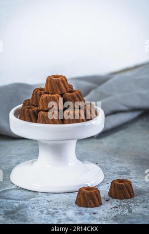 Pralinen aus Schokolade in Form von kleinen Bundt-Kuchen, mit Kakao bestaubt, auf hellgrauem Hintergrund, Kopierraum Stockfoto