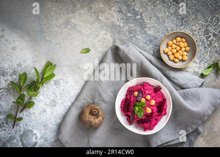 Schüssel mit Rote-Bete-Hummus auf rustikalem grauen Hintergrund, Draufsicht, Kopierbereich Stockfoto