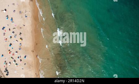 Ein unvergleichliches Luftfoto der wunderschönen Stadt Albufeira in Portugal, das den Strand Praia de Albufeira zeigt, mit Menschen, die sich im Urlaub entspannen Stockfoto