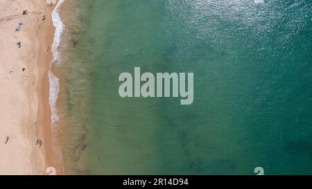 Ein unvergleichliches Luftfoto der wunderschönen Stadt Albufeira in Portugal, das den Strand Praia de Albufeira zeigt, mit Menschen, die sich im Urlaub entspannen Stockfoto