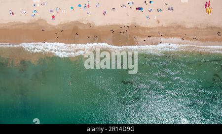 Direkt aus der Vogelperspektive von der wunderschönen Stadt Albufeira in Portugal, die den Strand Praia da Oura zeigt und Menschen, die sich im Urlaub auf der entspannen Stockfoto