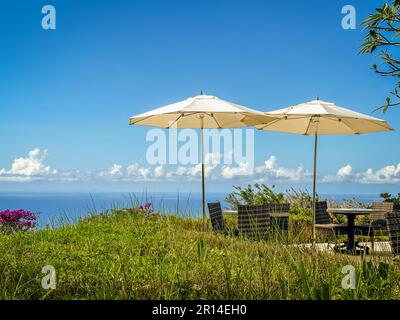 Restauranttische auf der Bergspitze unter Sonnenschirmen bieten einen Blick auf das Karibische Meer. Stockfoto