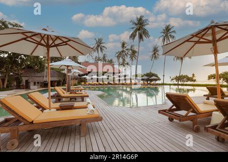 Swimmingpool in einem Hotel-Poolresort mit Sonnenschirmen, Strand und Stühlen Stockfoto