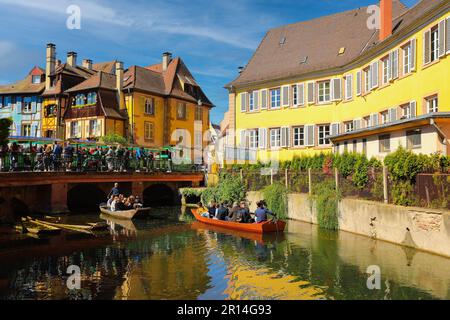 Traditionelle Fachwerkhäuser am Flussufer in Colmar, mit Touristen, die im Sommer eine Bootsfahrt entlang des Flusses Lauch machen, Elsass Rigon, Frankreich Stockfoto