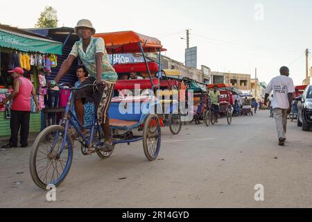 Toliara, Madagaskar - 01. Mai 2019: Abend auf einer typischen Straße der Stadt am Abend, Marktstände an der Seite, madagassische Menschen laufen, einige Fahrräder fahren, dre Stockfoto