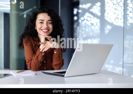 Nahaufnahme eines schönen lateinamerikanischen Geschäftsmannes, das lächelt und in die Kamera schaut, in einem modernen Büro arbeitet Stockfoto