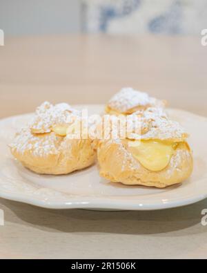 Drei Sahnepuffs, Pate a Choux, gefüllt mit Vanillecreme Pudding und gestreut mit Puderzucker. Süßes Dessert. USA. Stockfoto